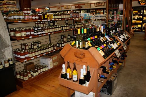 A well-stocked store interior featuring shelves of jars and a display of various wine bottles.