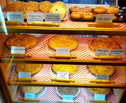 A display case filled with various baked goods, including cookies and different types of apple pies.