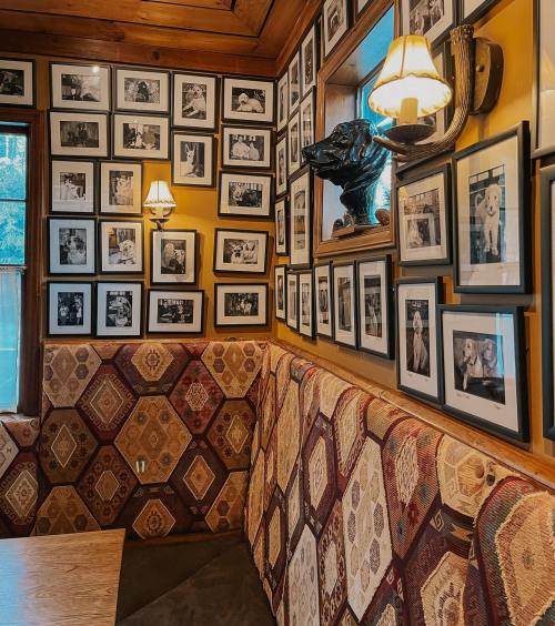 Cozy restaurant corner with patterned seating and walls adorned with framed black-and-white photos.