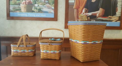 Three woven baskets of varying sizes, featuring colorful ribbon accents, displayed on a wooden table.