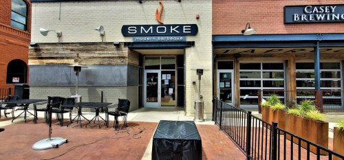 Exterior view of "Smoke Modern Barbecue" restaurant with outdoor seating and adjacent "Casey Brewing" establishment.