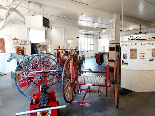A museum display featuring vintage horse-drawn carriages and historical artifacts in a bright, spacious room.