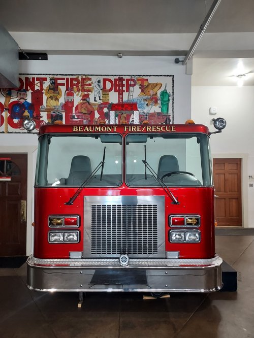 A red fire truck displayed indoors, with "Beaumont Fire/Rescue" on the front, against a colorful mural backdrop.