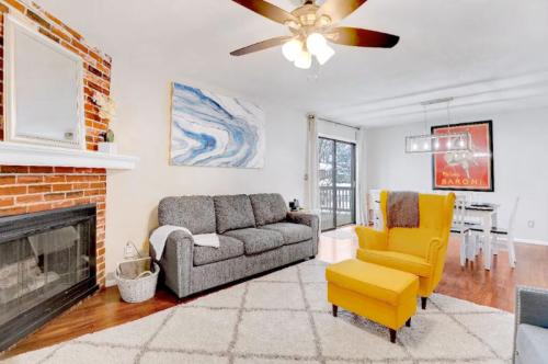 Cozy living room with a gray sofa, yellow armchair, brick fireplace, and dining area with a table and chairs.