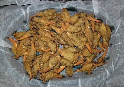 A platter of golden-brown fried crab claws arranged on parchment paper.