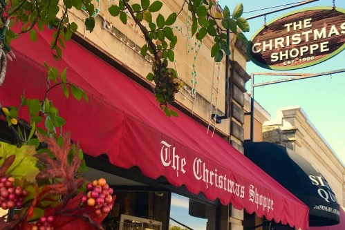A festive storefront with a red awning reading "The Christmas Shoppe" and holiday decorations.