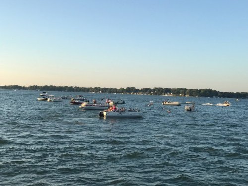 Boats on a calm lake during sunset, with people enjoying the water and clear blue skies.