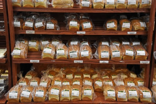 Shelves filled with various types of packaged bread loaves, neatly arranged in a store display.