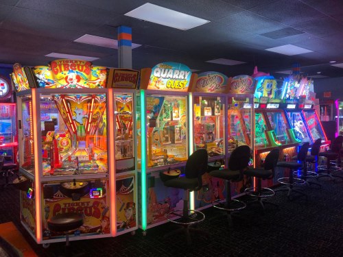 A brightly lit arcade featuring colorful pinball machines and game cabinets in a fun, vibrant setting.