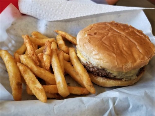 A hamburger with a soft bun and a slice of cheese, served with a side of golden, crispy French fries.