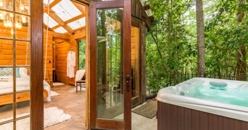 A hot tub sits next to a glass cabin in Texas.
