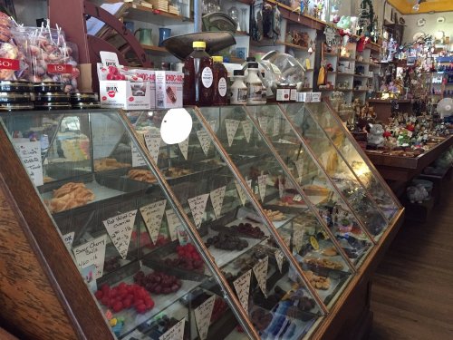 A cozy shop interior featuring a display case filled with pastries, candies, and various decorative items.