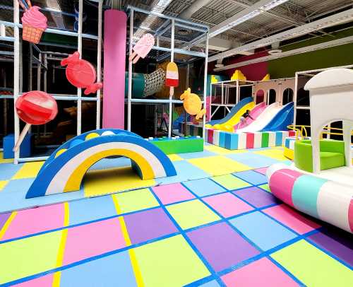 Colorful indoor play area with slides, soft mats, and playful decorations like ice cream and candy shapes.