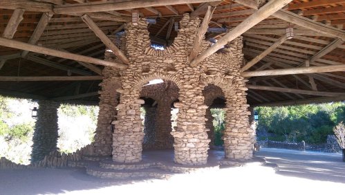 Stone structure with arches and wooden beams, set in a natural outdoor environment.