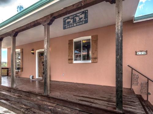 A rustic porch with wooden beams, a decorative sign, and a window, set against a peach-colored wall.