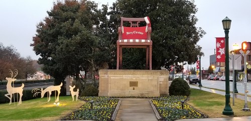 A large festive chair with a "Merry Christmas" sign, surrounded by holiday decorations and greenery.