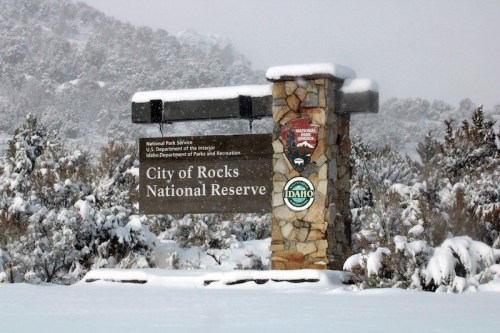 Sign for City of Rocks National Reserve, covered in snow, with logos of the National Park Service and Idaho Parks.