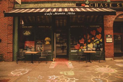 A cozy café with a striped awning, colorful heart decorations on the windows, and chalk art on the sidewalk.