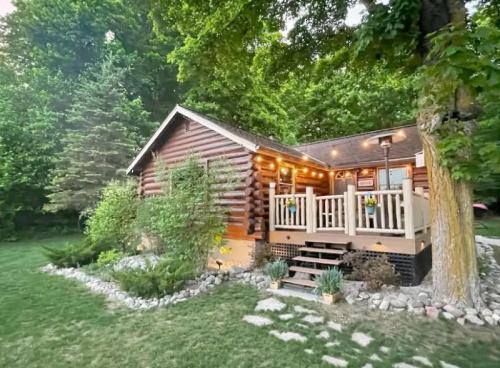 A cozy log cabin surrounded by greenery, featuring a welcoming porch and landscaped garden.