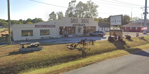 A vintage antique shop named "Dark Horse Antiques" with various collectibles displayed outside.