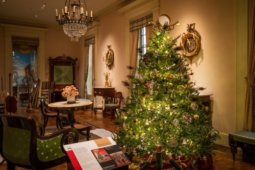 A beautifully decorated Christmas tree in an elegant room with vintage furniture and festive decor.