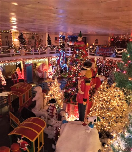 A festive indoor scene filled with Christmas trees, lights, decorations, and nutcracker figures, creating a holiday atmosphere.