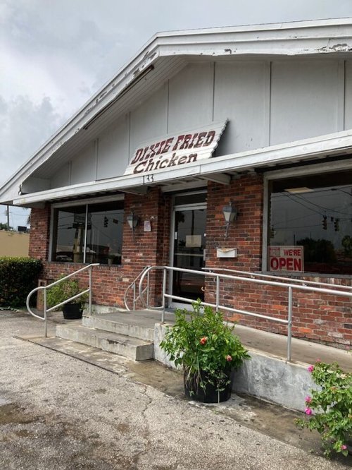 Exterior of a restaurant named "Dixie Fried Chicken," featuring brick walls and a sign indicating it's open.
