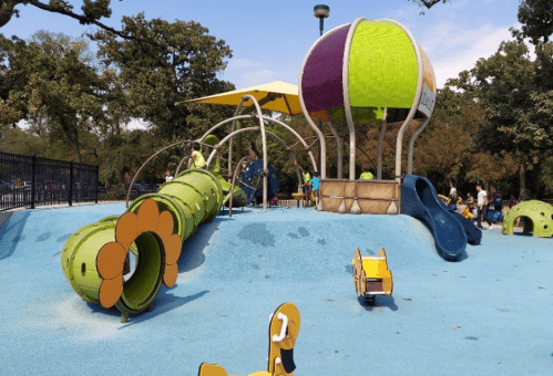 Colorful playground with a slide, climbing structures, and a large balloon-shaped play area on a blue surface.