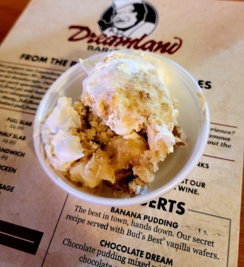 A bowl of banana pudding topped with whipped cream, placed on a menu background.