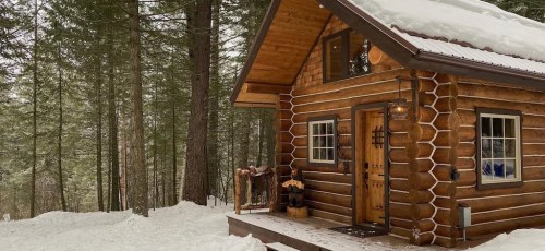 A cozy log cabin surrounded by snow-covered trees in a winter landscape.
