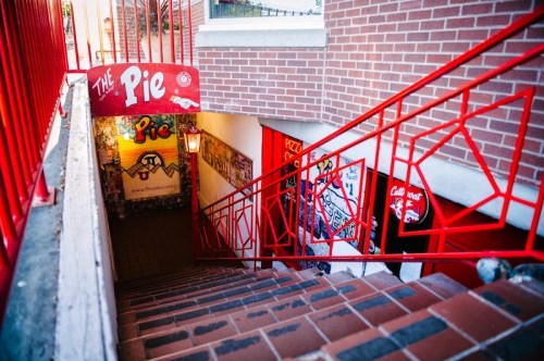 Staircase leading down to "The Pie" with red railings and colorful murals on the walls.