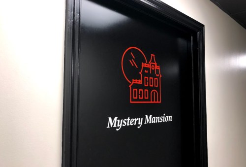 A black door with a red graphic of a mansion and the text "Mystery Mansion" below it.
