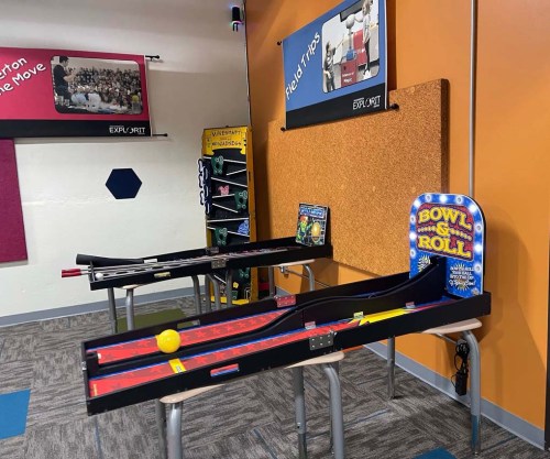 A game room featuring two bowling-themed arcade games with colorful lanes and a yellow bowling ball.