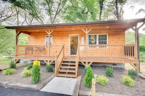 A wooden cabin with a front porch, surrounded by greenery and a pathway leading to the entrance.