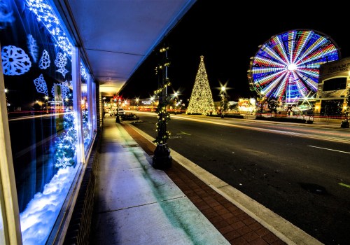 A festive street scene at night featuring a decorated tree, a colorful ferris wheel, and holiday lights.
