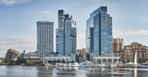 City skyline featuring modern skyscrapers and a marina with boats along a calm waterfront.