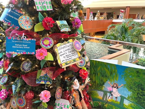 A decorated Christmas tree with colorful ornaments and a sign from Pelham Road Elementary School in a festive setting.