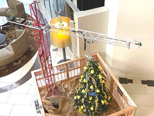 A model construction site featuring a crane and a decorated Christmas tree inside a wooden crate.