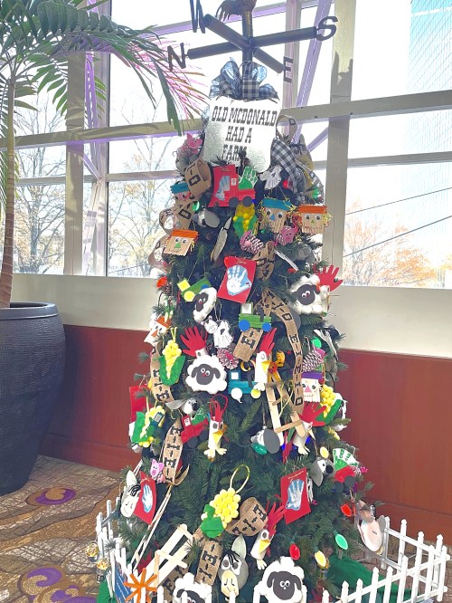 A festive Christmas tree decorated with colorful crafts, including animals and handprints, themed around "Old MacDonald Had a Farm."