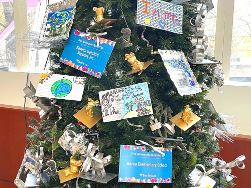 A decorated Christmas tree with colorful artwork and signs from Berea Elementary School and Eastern Illinois University.