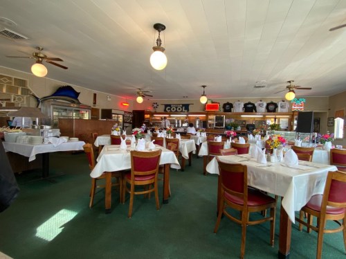 Interior of a restaurant featuring tables with white tablecloths, wooden chairs, and a cozy atmosphere.