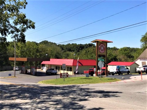 A small roadside motel with red roofs, surrounded by trees and a sign indicating the speed limit.