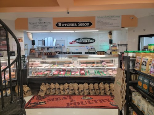 A butcher shop display featuring various meats, a red "MEAT & POULTRY" rug, and a sign above reading "Butcher Shop."