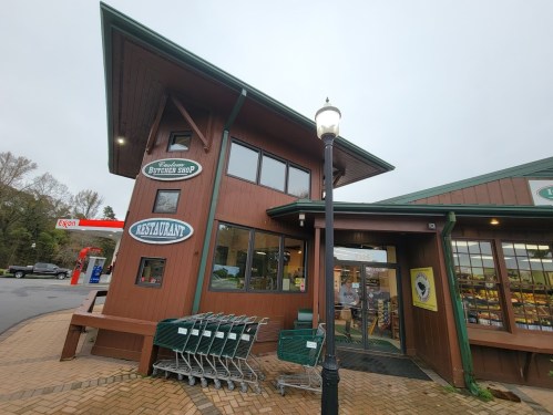 A wooden building with a sign for a restaurant and a butcher shop, featuring shopping carts outside.