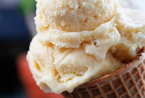 Close-up of a waffle cone filled with creamy vanilla ice cream scoops.