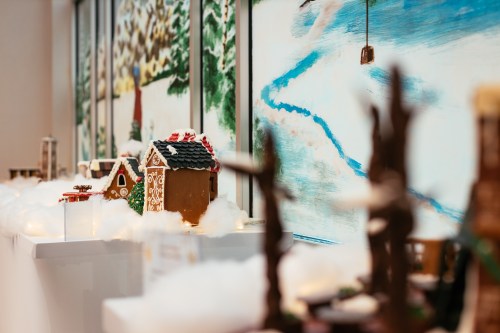 A festive display of gingerbread houses on a snowy surface, with a colorful winter scene in the background.