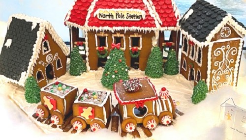 A festive gingerbread village featuring a North Pole station, decorated houses, trees, and a train, all covered in icing.