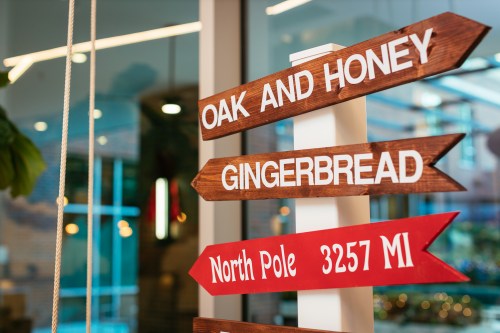 Wooden directional signs pointing to "Oak and Honey," "Gingerbread," and "North Pole 3257 MI."