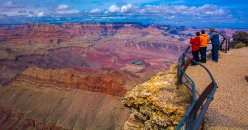 three people look at the grand canyon from a viewpoint, grand canyon national park in arizona