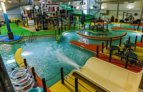 Indoor water park featuring slides, lazy river, and colorful play areas with seating and water features.